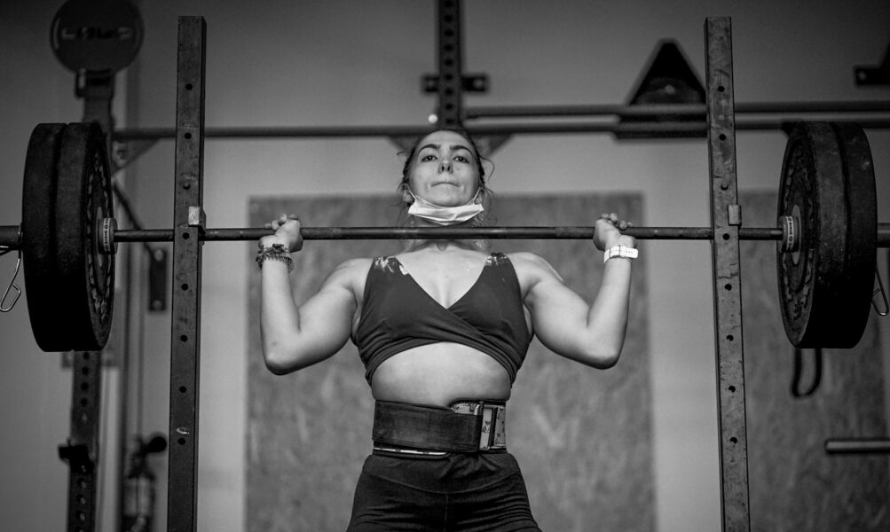 woman in black sports bra and black shorts holding gray metal bar