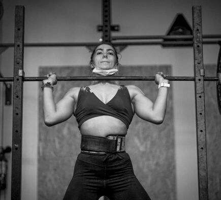 woman in black sports bra and black shorts holding gray metal bar